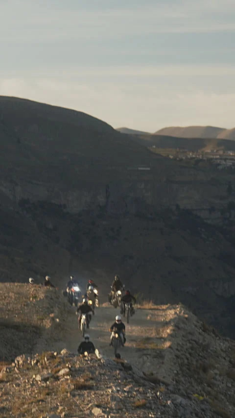 Daring Motorcycle Convoy Navigates Rugged Mountain Trail in Early Evening Light Stock Footage 273794121