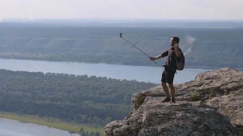 Daring traveler shoots himself with a camera on top of a mountain 動画素材 72587589