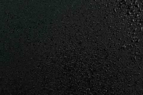 A dark abstract background of water drops on flat black rubber surface Stock Photos