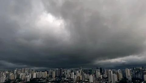 Dark and dramatic rain clouds over a city. Stock Photos