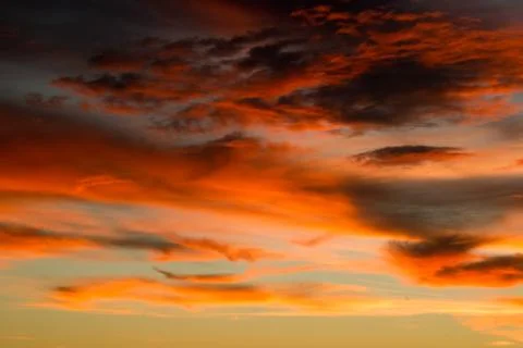 Dark and light orange colored sky of clouds during sunset. Stock Photos