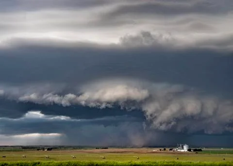 Dark and light wall clouds spin below a tornado super-cell kicking up dust into Stock Photos