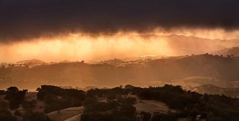 Dark and menacing storm clouds covering the sky at sunset; bright orange li.. Stock Photos