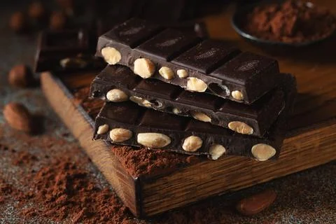 Dark and milk chocolate with nuts on a dark background sprinkled with cocoa.. Stock Photos