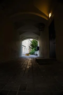 A dark arched passage with a light at the end Stock Photos