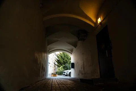 A dark arched passage with a light at the end Stock Photos