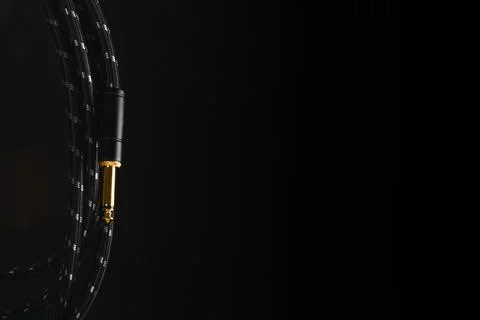 Dark background with an audio cable with trs jack plug against a black backgr Stockfoto's