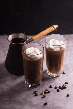 On a dark background, a coffee maker and glasses with cold iced coffee and wh Stock Photos