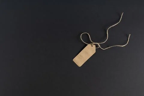 On a dark background, an empty shopping label, a price tag made of craft pape Stock Photos