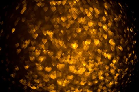 Dark background with golden bokeh in the shape of a heart. Stock Photos