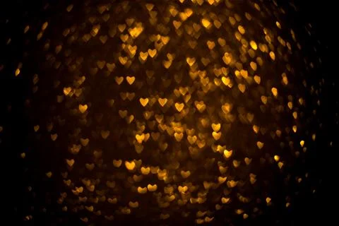 Dark background with golden bokeh in the shape of a heart. Stock Photos