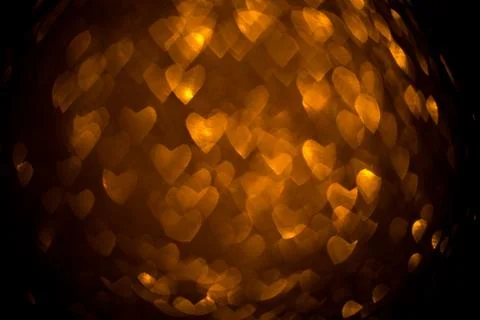 Dark background with golden bokeh in the shape of a heart. Stock Photos