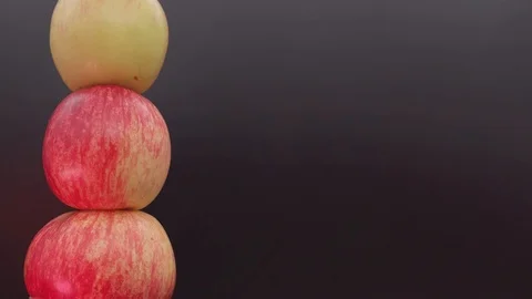 Dark background for text. On the left, three apples are spinning vertically. Stock Footage 114660420