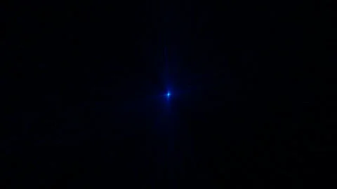 On a dark background, there is a blue light source and rays and particles go Stock Footage 265474416