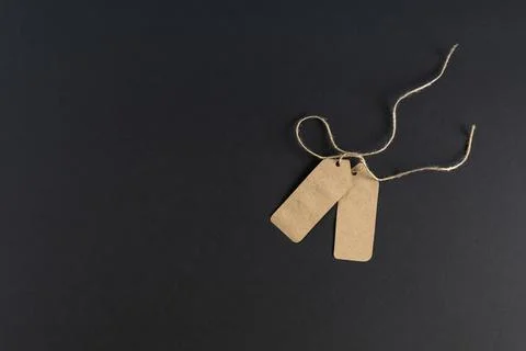 On a dark background, two blank trade labels, price tags from kraft paper wit Stock Photos
