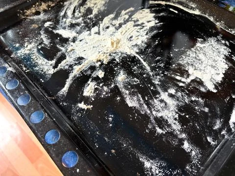 A dark baking sheet covered with flour, dough scraps, and flour dust from making Stock Photos