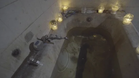Dark bathroom with water drops from a leaky tap lit by cemetery candles 3 Stock Footage 89620232