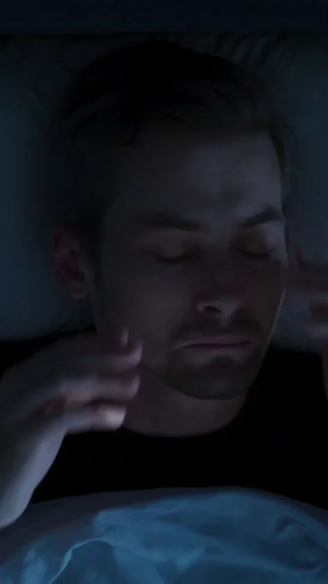 In a dark bedroom, a man wakes up because of sleep paralysis or nightmare Stock Footage 315992525