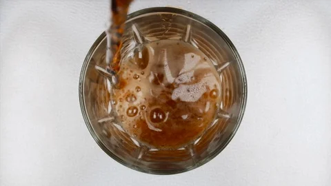 Dark beer with foam and bubbles slowly pours into the glass Stock Footage 129410751