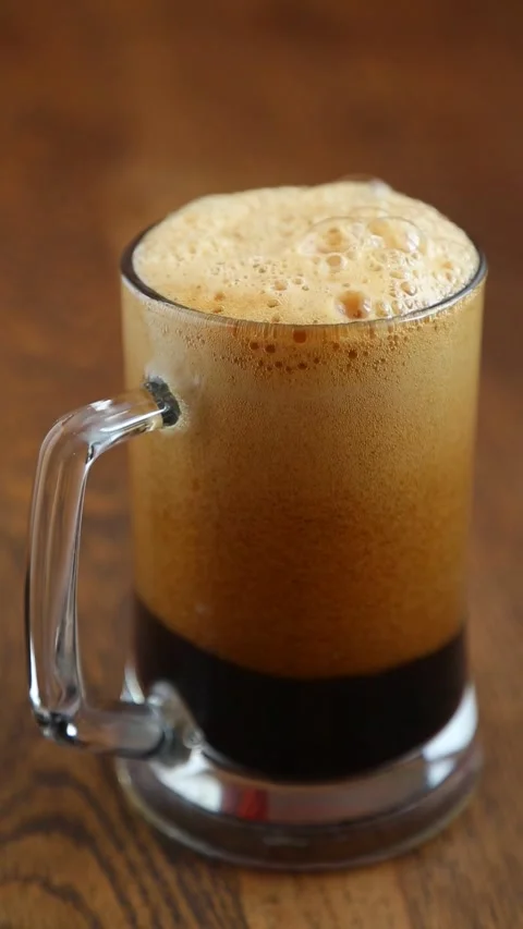 Dark beer pouring into glass mug creating thick foam head Vídeos de archivo 311539745