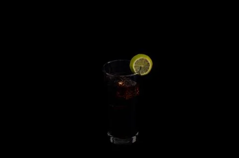 Dark beverage with lime slice on black background Stock Photos