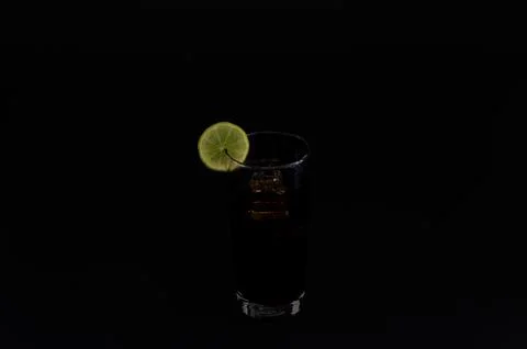 Dark beverage with lime slice on black background Stock Photos