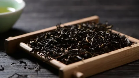 Dark Black Tea Leaves Falling in Slow Motion into Wooden Tray Stock Footage 339642220