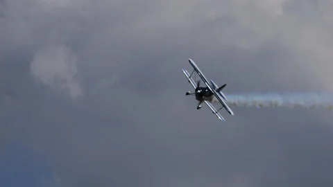 Dark blue and white light biplane does extreme acrobatic maneuvers in the sky Stock Footage 218573674