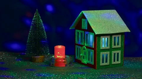 On a dark blue background between the tree and the house a candle flickers Stock Footage 288114643