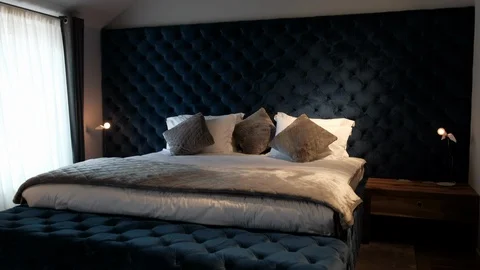 Dark blue bed, bedroom interior. Soft pillows on the bed Stock Footage 102866287