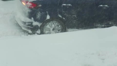 Dark blue car stuck in deep snow during winter blizzard, back wheel spinning on Stock Footage 344095775
