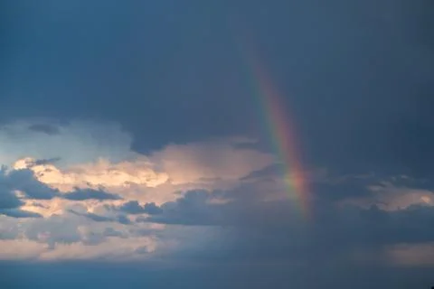 Dark blue clouds and light rainbow on the sky Stock Photos