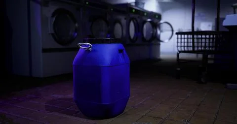 Dark blue container in a dimly lit laundry room with washing machines 스톡 일러스트