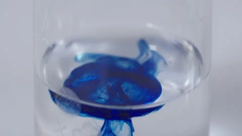 Dark blue drop is being adding to clear liquid in the flask. close-up of mixing Stock Footage 201344686