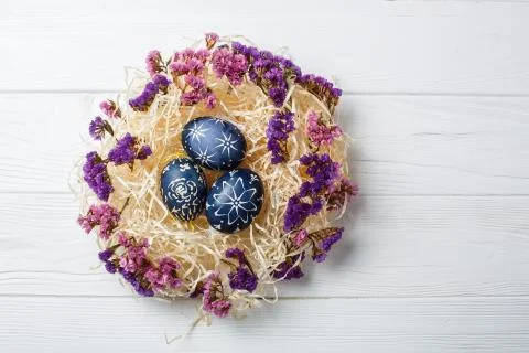 Dark blue easter eggs in nest on white wooden background Stock Photos