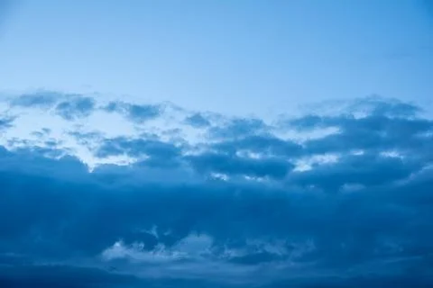 Dark blue evening sky with clouds. Blue hour. Heavenly natural background to  Stock Photos