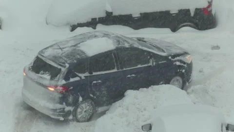 Dark blue hatchback car stuck in deep snow drift during severe winter snowstorm, Stock Footage 344846931