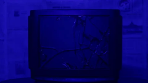 In a dark blue room, they smash the TV with a bat. Stock Footage 221623587