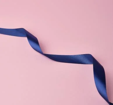 Dark blue silk ribbon twisted into loops on a pink background Stockfoto's