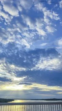 Dark blue sky with clouds over trees and water surface. Evening sunset. Фото