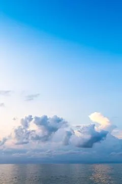 Dark blue sky with cumuli clouds in over calm sea Stock Photos
