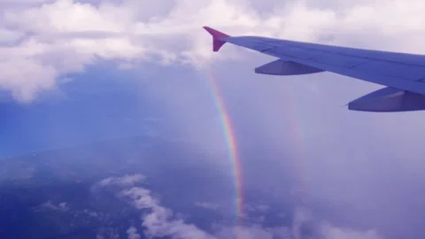 Dark blue sky with rainbow n airplane wing over sea beach Stock Footage 299799475