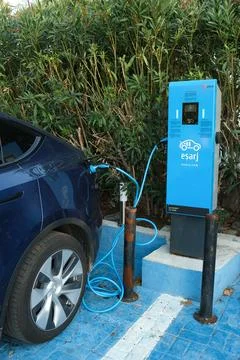 Dark blue Tesla Model Y is charging at outdoor in a charging station known .. Stock Photos