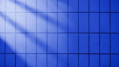 A dark blue tiled wall background with light rays cast across the surface, .. Stock Photos