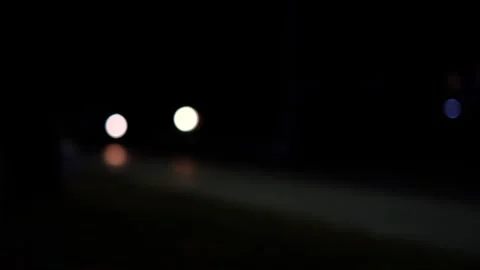 A dark, blurry image of a road with a car in the foreground. Stock Footage 295198609