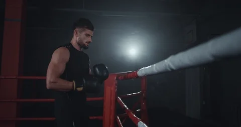 In a dark boxing ring attractive strong fit body guy have a break after a Stock Footage 117053313