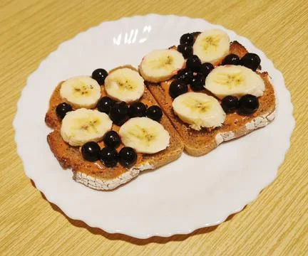 Dark bread with peanut butter, black currant and banana slices Stock Photos