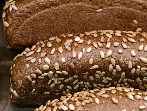 Dark bread shaped like a brick and topped with sunflower seeds, displayed i.. Stock Photos