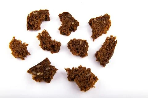 Dark broken pieces of bread on a white background. Stock Photos