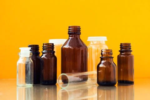 Dark brown phials on yellow background. Small empty bottles Stock Photos